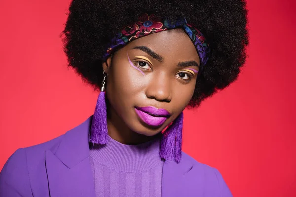 Africano americano jovem mulher em roxo elegante roupa isolada no fundo vermelho — Fotografia de Stock