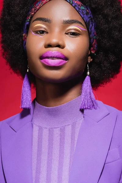 Mujer joven afroamericana en traje elegante púrpura aislado en rojo - foto de stock