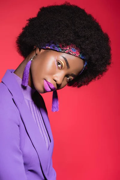 Mujer joven afroamericana en traje elegante púrpura aislado en rojo - foto de stock
