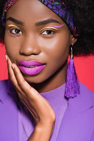 Афро-американська молода жінка в фіолетовому стильному вбранні ізольована на червоному — Stock Photo