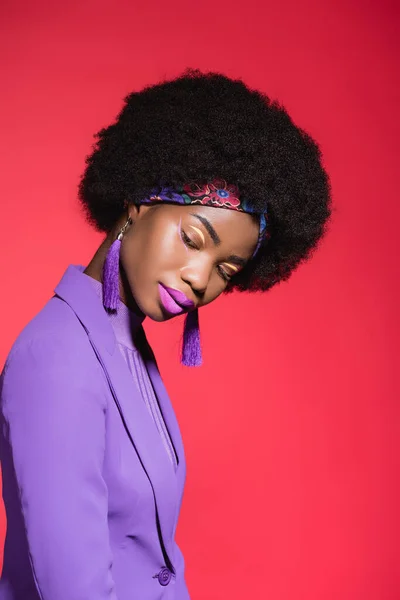 African american young woman in purple stylish outfit isolated on red — Stock Photo