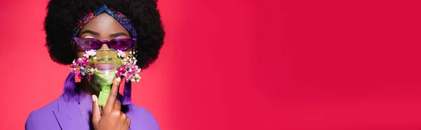 Afro-américaine jeune femme en costume violet élégant avec des fleurs dans inhalateur isolé sur rouge, bannière — Stock Photo