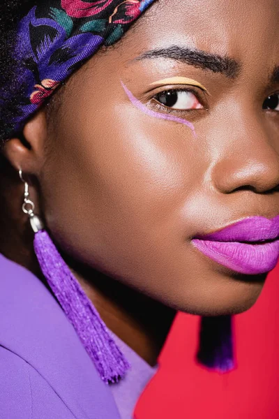 Closeup of african american young woman in purple stylish outfit isolated on red — Stock Photo