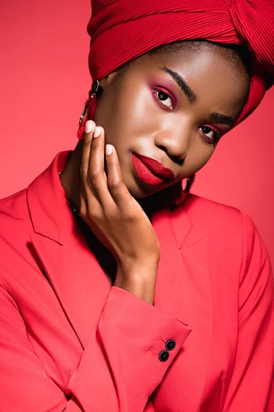 Mujer joven afroamericana en traje elegante y turbante aislado en rojo - foto de stock