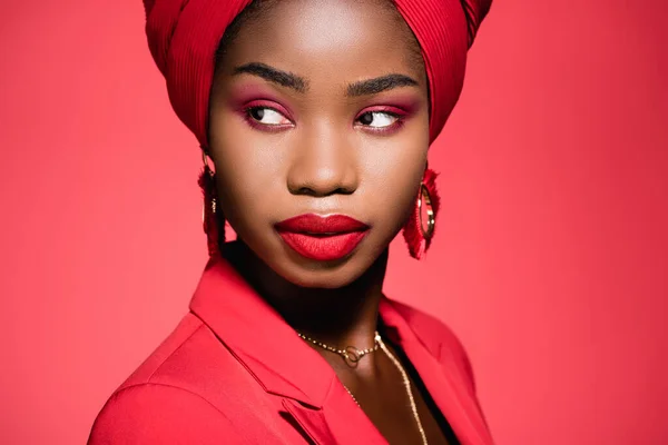 Afro-américaine jeune femme en tenue élégante et turban isolé sur rouge — Photo de stock