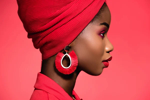 Profile of african american young woman in stylish outfit and turban isolated on red — Stock Photo