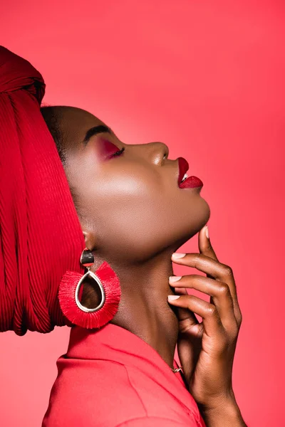 Perfil da jovem americana africana em roupa elegante e turbante com olhos fechados isolados no vermelho — Fotografia de Stock