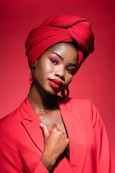 Afro-américaine jeune femme en tenue élégante et turban isolé sur rouge — Photo de stock