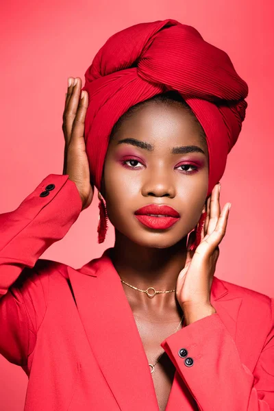 Mujer joven afroamericana en traje elegante y turbante aislado en rojo - foto de stock