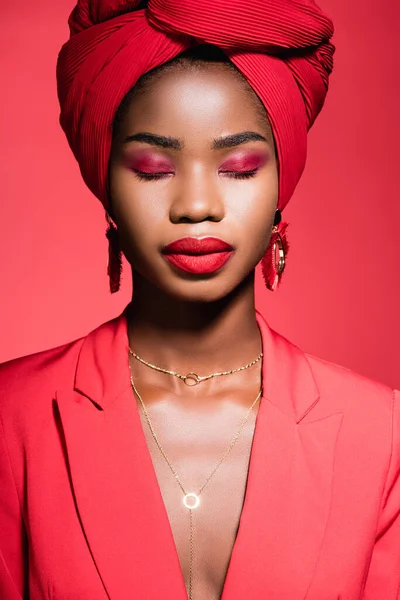 Afro-américaine jeune femme en tenue élégante et turban avec les yeux fermés isolé sur rouge — Photo de stock
