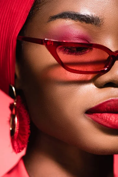 Primer plano de mujer joven afroamericana en gafas de sol y turbante aislado en rojo - foto de stock