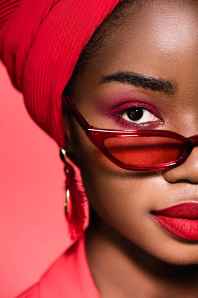 Gros plan de afro-américaine jeune femme en lunettes de soleil et turban isolé sur rouge — Photo de stock