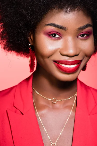 Smiling african american young woman in stylish outfit isolated on red — Stock Photo