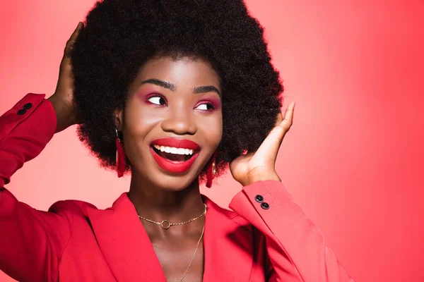 Happy african american young woman in stylish outfit isolated on red — Stock Photo