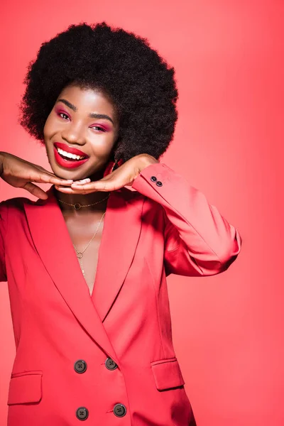 Heureux afro-américain jeune femme en tenue élégante isolé sur rouge — Photo de stock