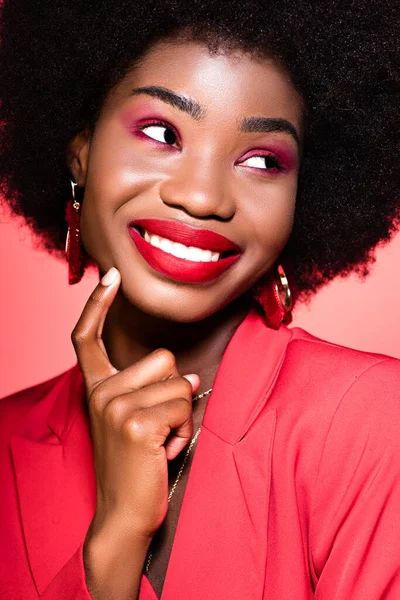 Happy african american young woman in stylish outfit isolated on red — Stock Photo