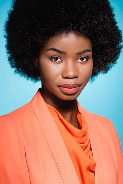 African american young woman in orange stylish outfit isolated on blue — Stock Photo