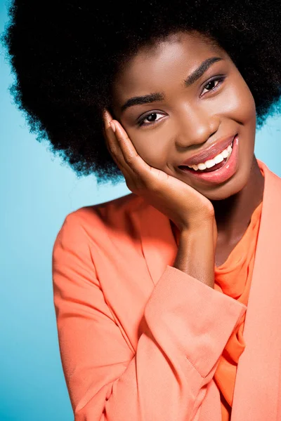 Sonriente afroamericana joven mujer en naranja elegante traje aislado en azul - foto de stock
