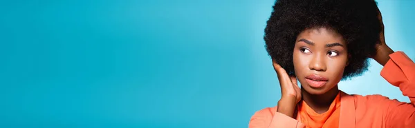 Mujer joven afroamericana en traje elegante naranja aislado en azul, bandera - foto de stock