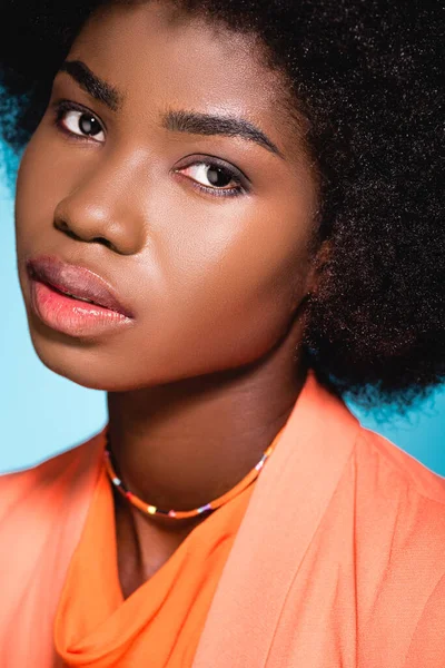 African american young woman in orange stylish outfit isolated on blue — Stock Photo