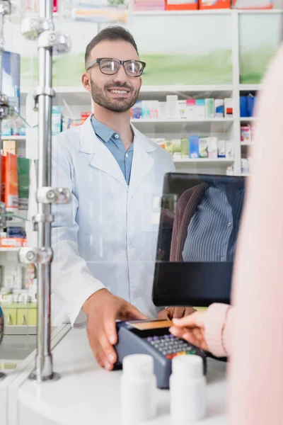 Client payant par carte de crédit sur le terminal de paiement près heureux vendeur en pharmacie — Photo de stock