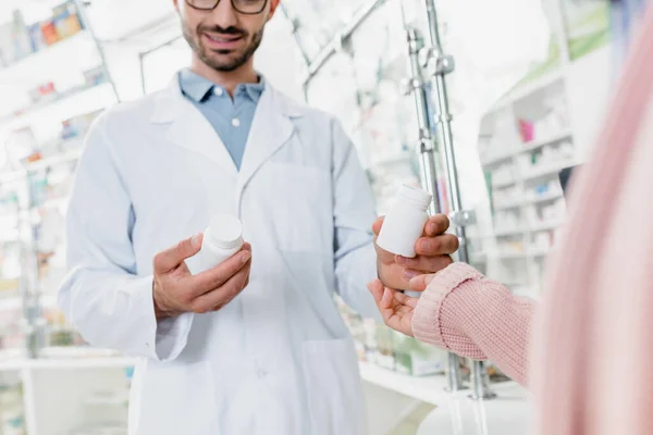 Ausgeschnittene Ansicht von Apotheker gibt Flasche mit Pillen an Kundin in Drogerie — Stockfoto