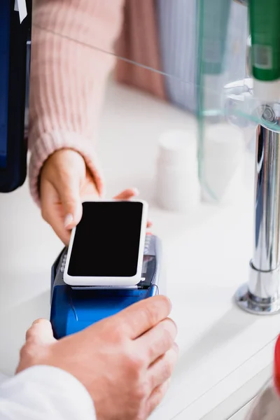 Cropped view of woman paying with smartphone in drugstore — Stock Photo