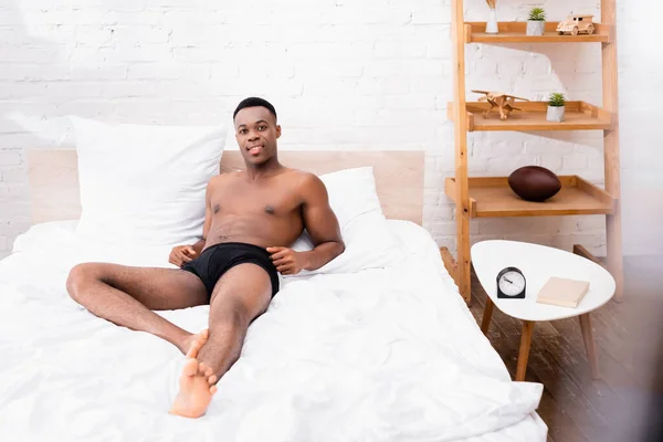 Afroamerikaner in Unterwäsche schaut Kamera auf Bett an — Stockfoto