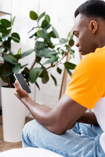 Smartphone avec écran blanc en main de l'homme afro-américain à la maison — Photo de stock