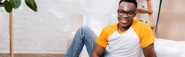 Sonriente hombre afroamericano en gafas mirando a la cámara en casa, pancarta - foto de stock