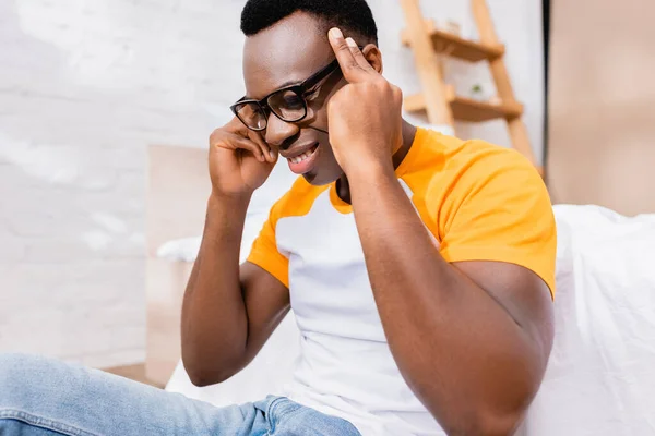 Homme afro-américain souffrant de maux de tête près du lit à la maison — Photo de stock