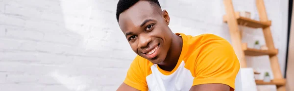 Jeune homme afro-américain souriant à la caméra à la maison, bannière — Photo de stock