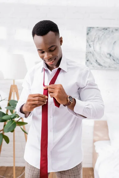 Alegre hombre de negocios afroamericano con corbata roja en casa - foto de stock