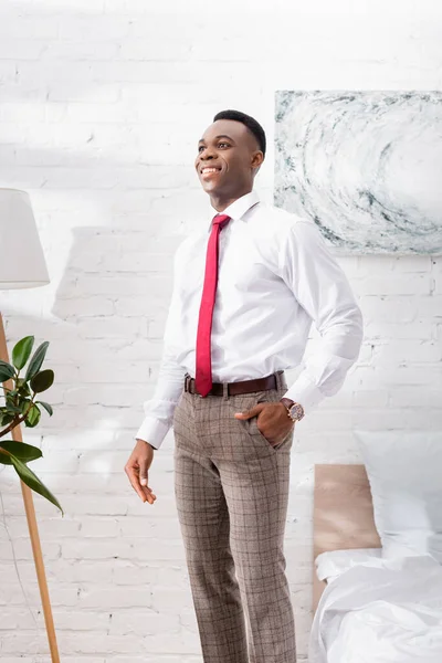 Smiling african american businessman standing near bed at home — Stock Photo