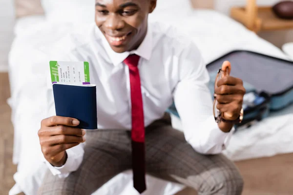 Passaporte com bilhete de avião e óculos em mãos de empresário afro-americano em fundo embaçado — Fotografia de Stock