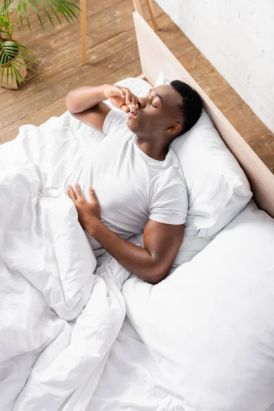 Vue grand angle de l'homme afro-américain dormant sur le lit le matin — Photo de stock