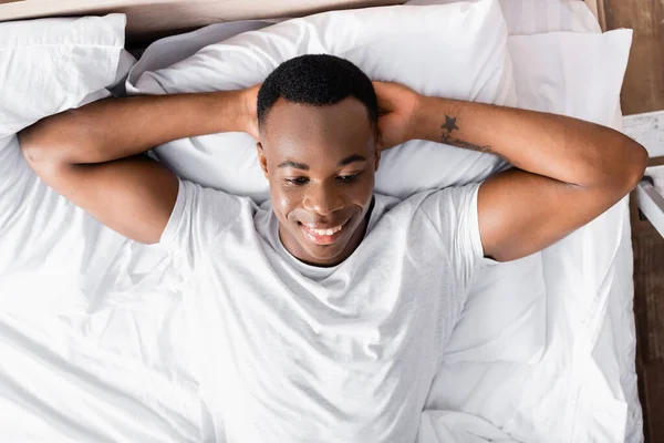 Top view of smiling african american man lying on bed — Stock Photo