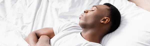 Homme afro-américain dormant sur une literie blanche, bannière — Photo de stock