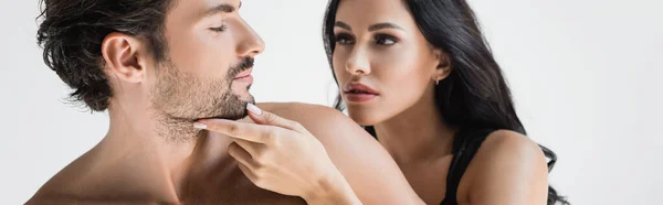 Brunette woman touching chin and looking at shirtless man isolated on white, banner — Stock Photo