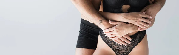 Cropped view of man in underpants embracing girlfriend in bra and panties isolated on grey, banner — Stock Photo