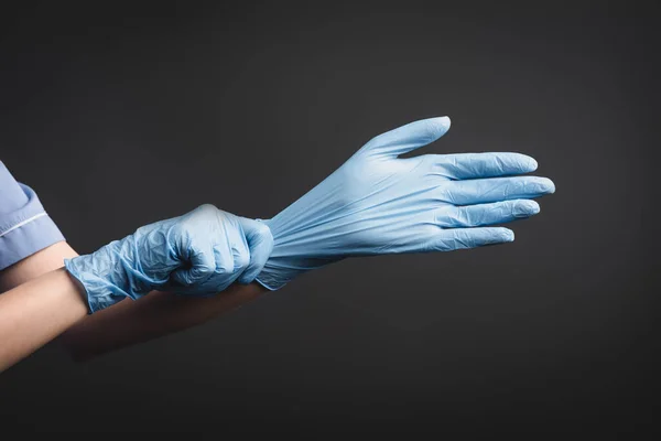 Visão recortada da enfermeira usando luvas de látex isoladas em cinza escuro — Fotografia de Stock