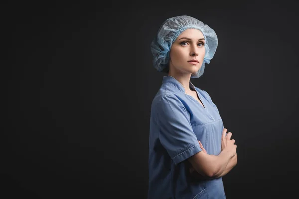 Infirmière en casquette médicale debout avec bras croisés isolés sur gris foncé — Photo de stock