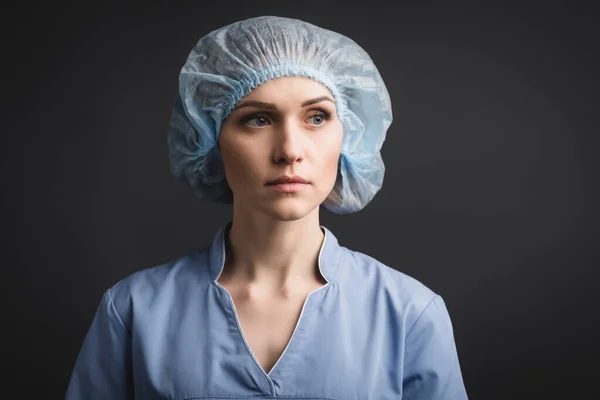 Enfermeira em tampa médica olhando para longe isolado em cinza escuro — Fotografia de Stock