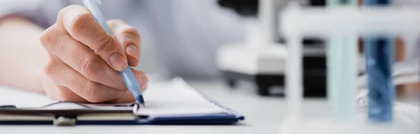 Cropped view of nurse writing on clipboard, banner — Stock Photo