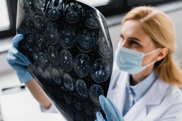 Rayons X dans les mains du scientifique en masque médical et gants en latex sur fond flou — Photo de stock