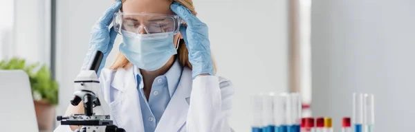 Müder Wissenschaftler in medizinischer Maske und Brille mit Kopfschmerzen im Labor, Banner — Stockfoto