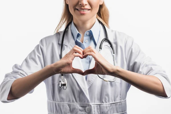 Recortado vista de feliz enfermera en blanco abrigo mostrando escucha signo con las manos aisladas en blanco - foto de stock