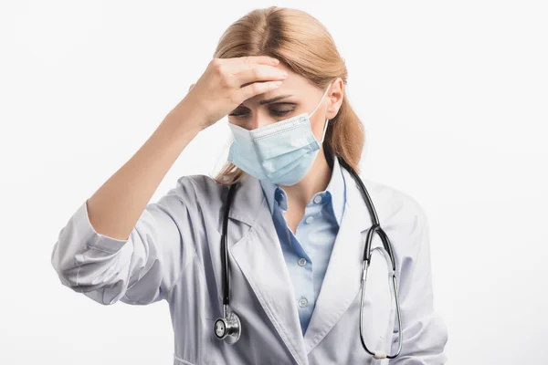 Nurse in medical mask and white coat suffering from headache isolated on white — Stock Photo