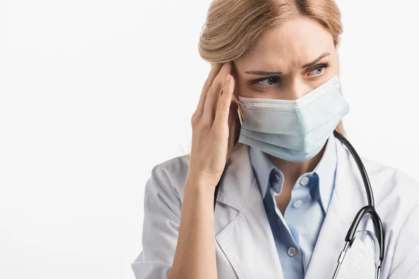 Nurse in medical mask and white coat suffering from migraine isolated on white — Stock Photo