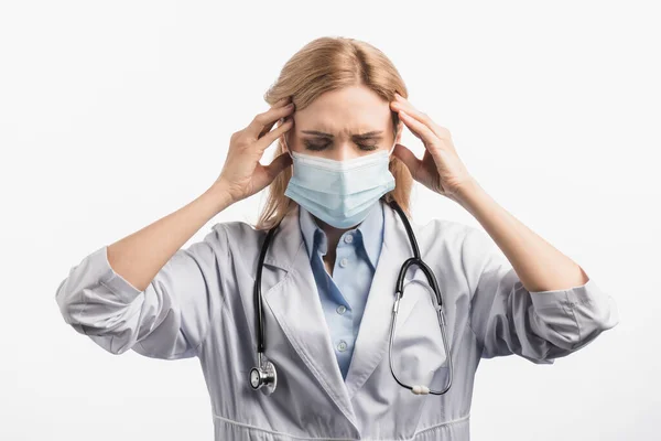 Infermiera stanca in maschera medica e camice bianco con mal di testa isolato su bianco — Foto stock